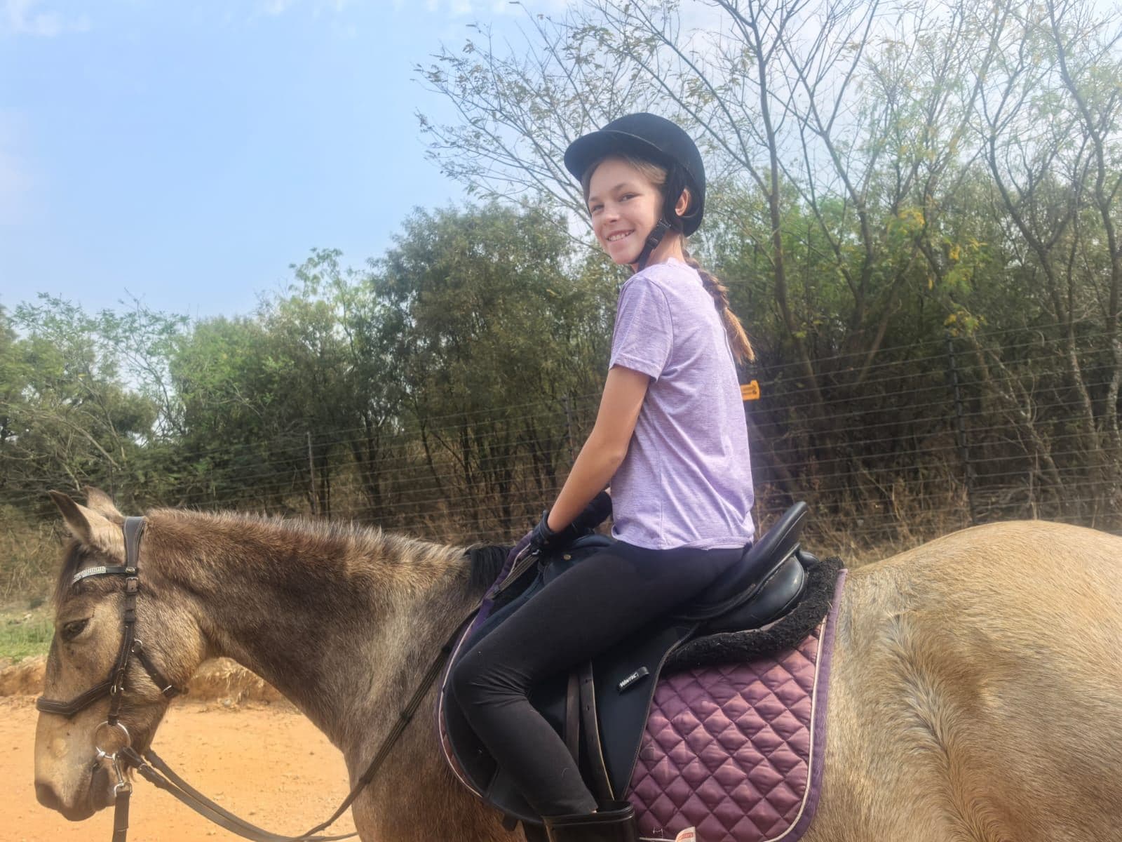 A smiling rider on a buckskin horse