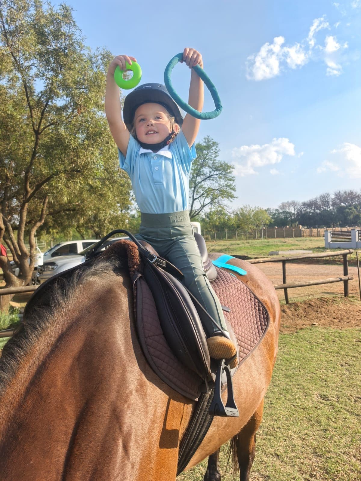 Young rider holding up rings during a riding game