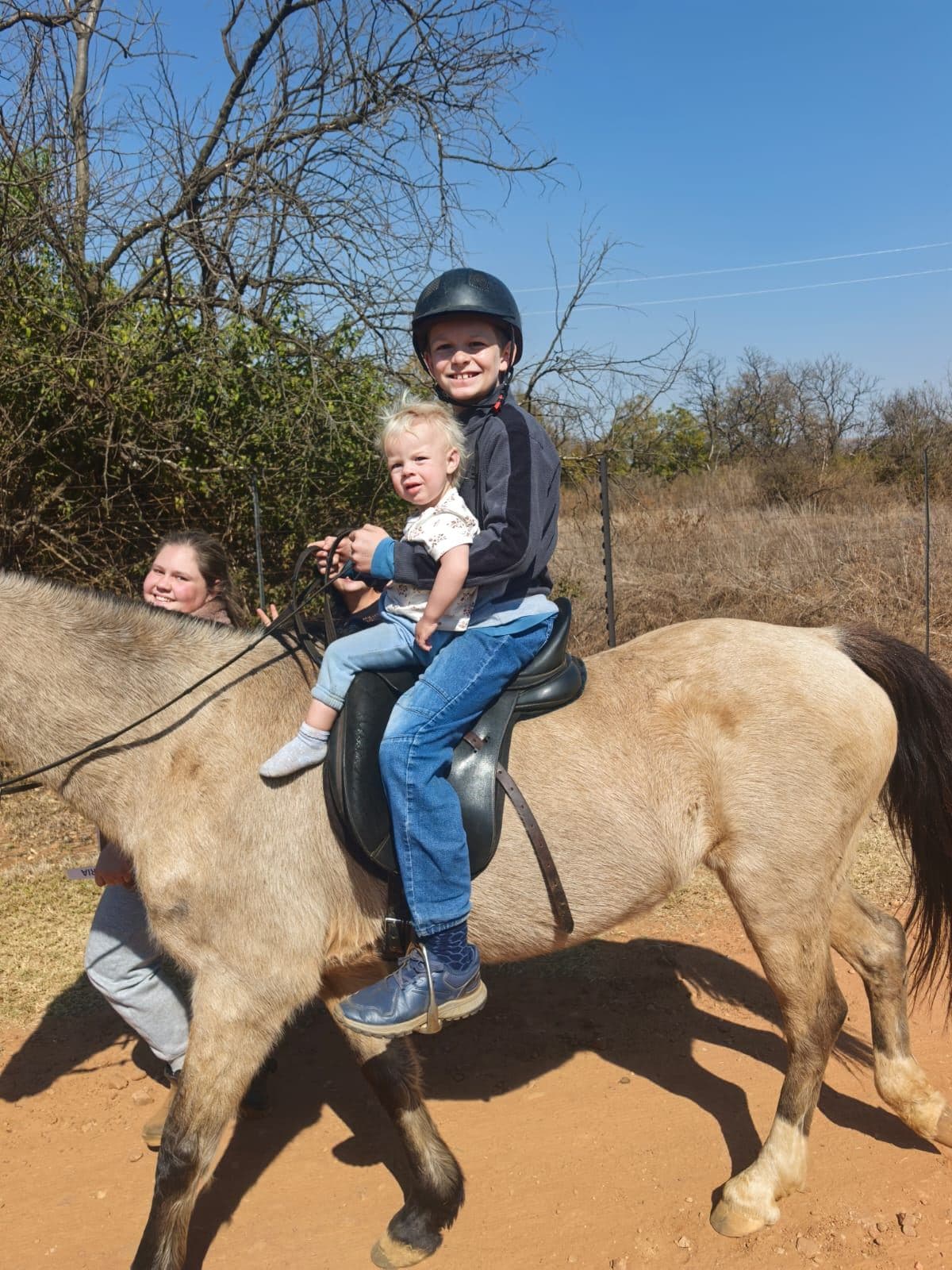 Two children riding together on a buckskin horse